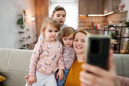 Mother and her three little daughters taking selfies at home