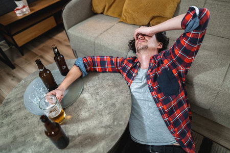 Drunk young man suffering from hangover at home