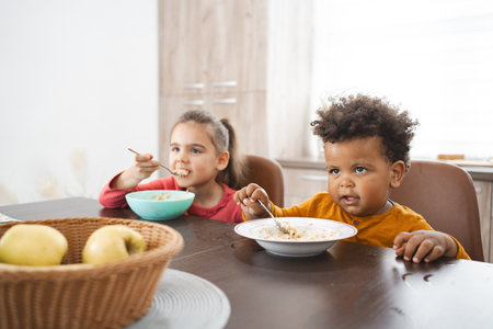 Multiracial children enjoy breakfast together at home during morningの写真素材