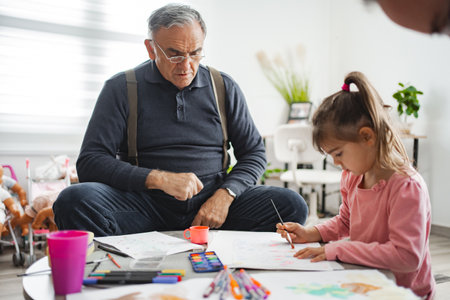 Grandpa and granddaughter make art in cozy roomの写真素材