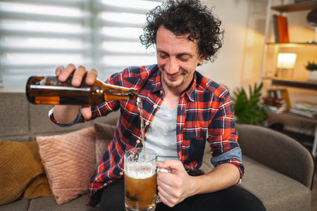 Young man pouring beer into glass at home