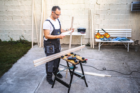 Mature male carpenter working with wooden plank outdoorsの写真素材