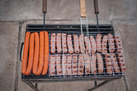 Sizzling sausages and hot dogs grilling at a summer barbecue gathering