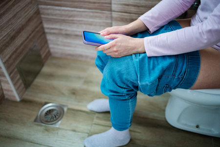 Relaxing moment on the toilet while scrolling through a smartphoneの写真素材