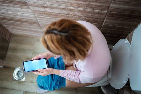 Relaxing moment while engrossed in smartphone activity indoorsの写真素材