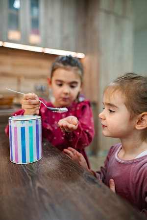 Creative moment of two children mixing colorful substance in a kitchen with wooden accents during a playful afternoonの写真素材