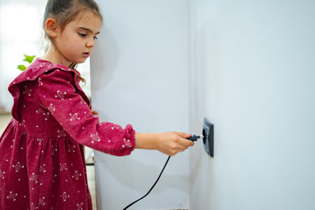 Young girl exploring electricity by plugging in a device in a cozy indoor space during daylight