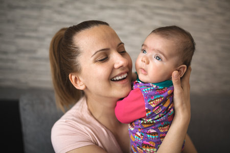 Smiling mother holding newborn baby girl at home