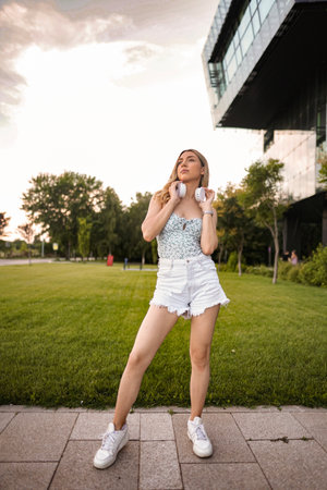 Portrait of beautiful blonde woman with white headphones in outdoorの写真素材