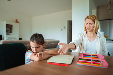 Child and parent in conflict over schoolwork at homeの写真素材