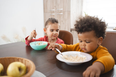Multiracial siblings enjoying breakfast at home on a sunny morningの写真素材