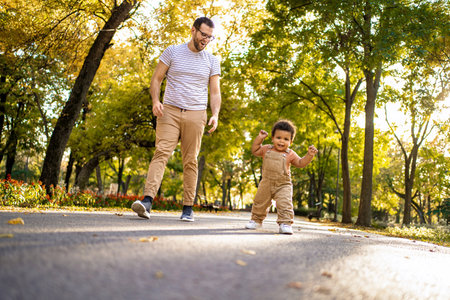 Joyful moments shared between father and toddler in autumn parkの写真素材