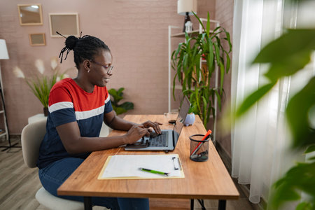 Focused individual working on a laptop in a stylish home officeの写真素材