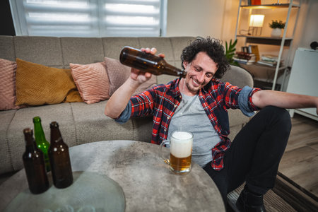 Man pouring beer into glass at homeの写真素材