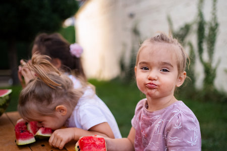 Sweet summer moments at a childrens picnic enjoying watermelon slicesの写真素材