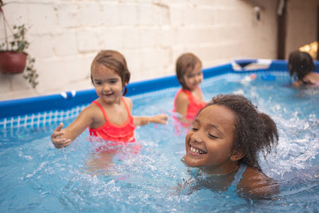 Children playing joyfully in a backyard pool during a summer afternoon