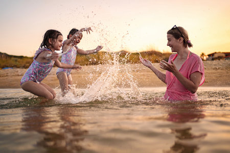 Joyful family splashing in ocean waves at sunset beach retreatの写真素材