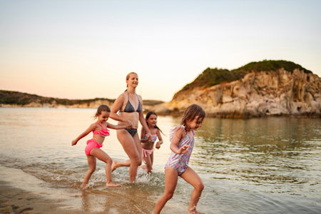 Family enjoying a joyful day at the beach with laughter and wavesの写真素材
