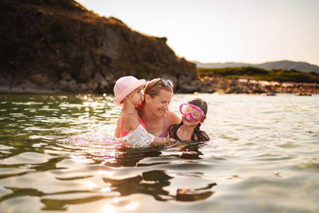 Family enjoys a joyful swim in the warm waters of a summer beachの写真素材