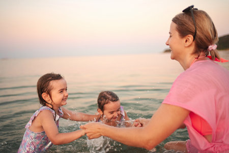 Joyful family moments splashing in the ocean at sunsetの写真素材