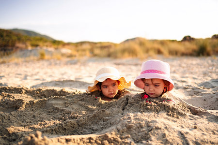 Children enjoying sandy fun under the sunny sky at the beachの写真素材