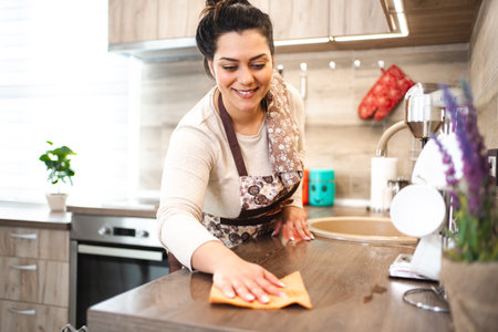 Woman in apron cleaning kitchen counter
