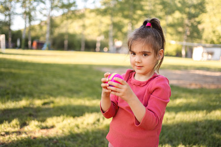Cute little girl is holding a ball on the playground