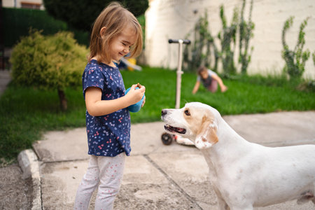 Joyful moments between a child and a friendly dog in the gardenの写真素材