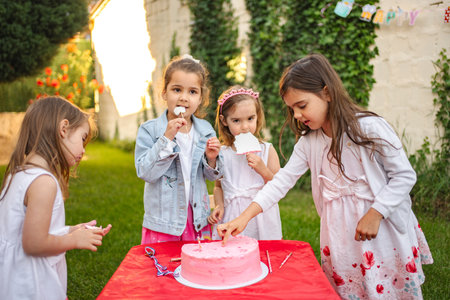 Kids enjoy cake at a joyful outdoor partyの写真素材
