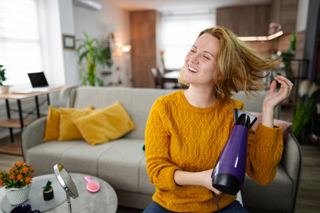 Woman Sitting on Couch Holding Hair Dryer