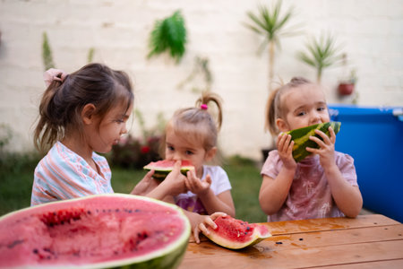 Children delight in summer watermelon feast in backyard gardenの写真素材