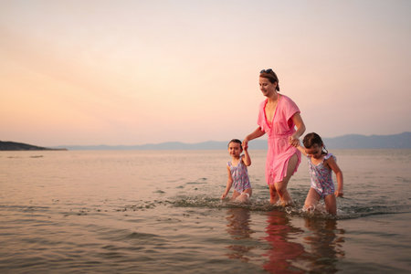 Joyful moments of family splashing in gentle waves at sunsetの写真素材