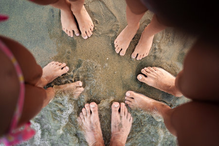Family enjoying a sunny day at the beach with playful toes in the sandの写真素材