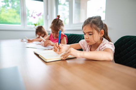 Children engaged in creative writing at a sunlit tableの写真素材