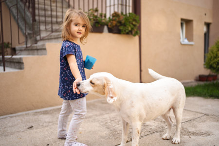 Little girl enjoying a playful moment with her dog in the yardの写真素材