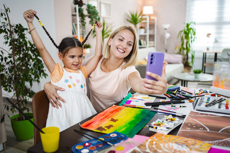 Mother and daughter enjoy a creative art session at home, capturing a joyful selfieの写真素材