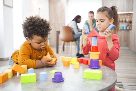 Multiracial children building blocks at home during daytime playの写真素材