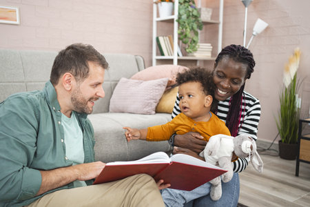 Multiracial family reading together at home on a cozy afternoonの写真素材