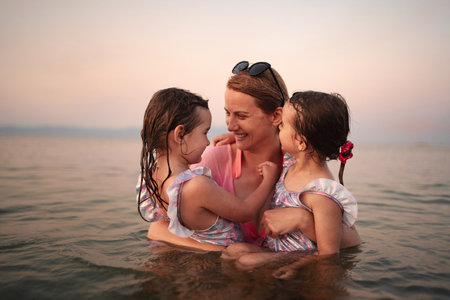 Joyful family bonding at the beach during sunsetの写真素材