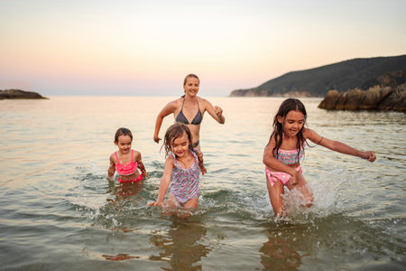 Joyful family splashes in the warm waters during sunset beach outingの写真素材