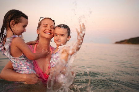 Joyful family playing in the water at a beautiful beach sunsetの写真素材