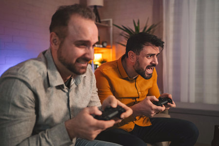 Friends engaged in an intense gaming session at home during the evening, enjoying a competitive...