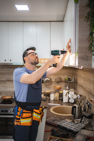 Handyman installing kitchen cabinets using a cordless screwdriverの写真素材
