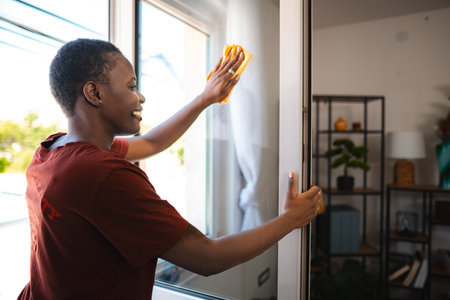 Young Woman Cleaning Windows in her Modern Apartment