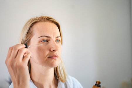 Woman applying essential oil on her face for skin care treatment
