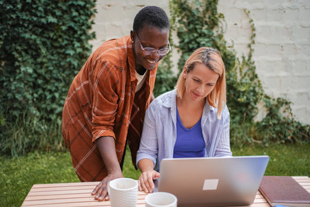 Two businesswomen working on a laptop outdoorsの写真素材