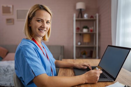 Female doctor is making an online purchase using her credit card and laptopの写真素材