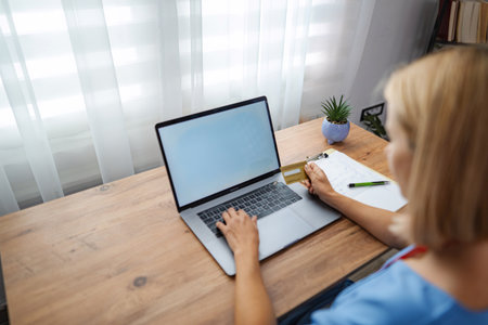 Female doctor making online payment using laptop and credit cardの写真素材