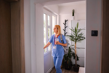 Female Doctor Leaving Home for Work, Holding Backpack and Coffeeの写真素材