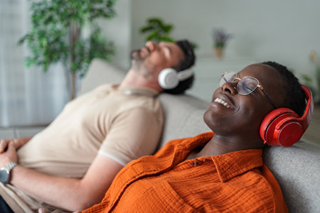 Couple relaxing on sofa listening to music with headphonesの写真素材
